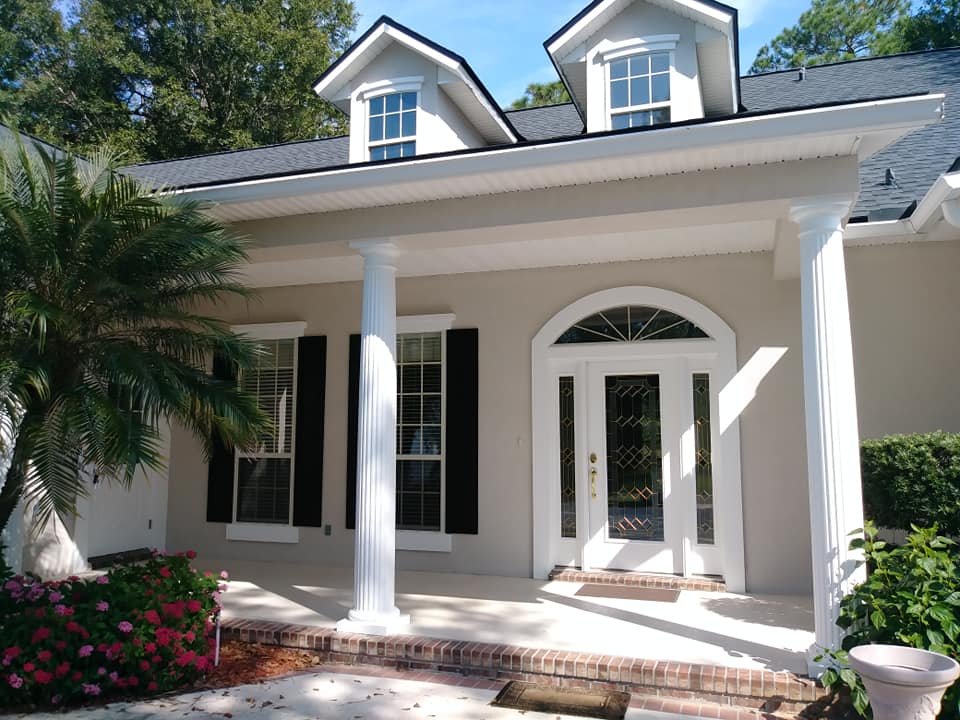 Exterior house painting project completed by A New Leaf Painting in Eagle Harbor, Fleming Island FL — white stucco with black shutters